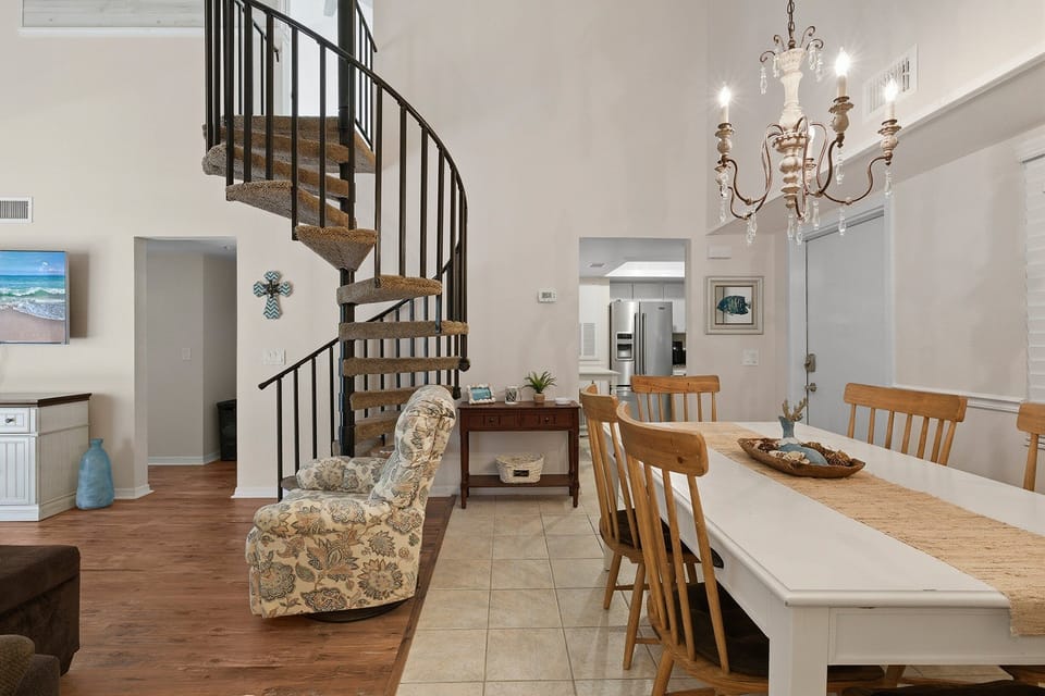 Bright and airy beach stay featuring a charming spiral staircase, coastal décor, and open dining space. This inviting vacation rental offers the perfect blend of comfort and style for your relaxing seaside getaway.