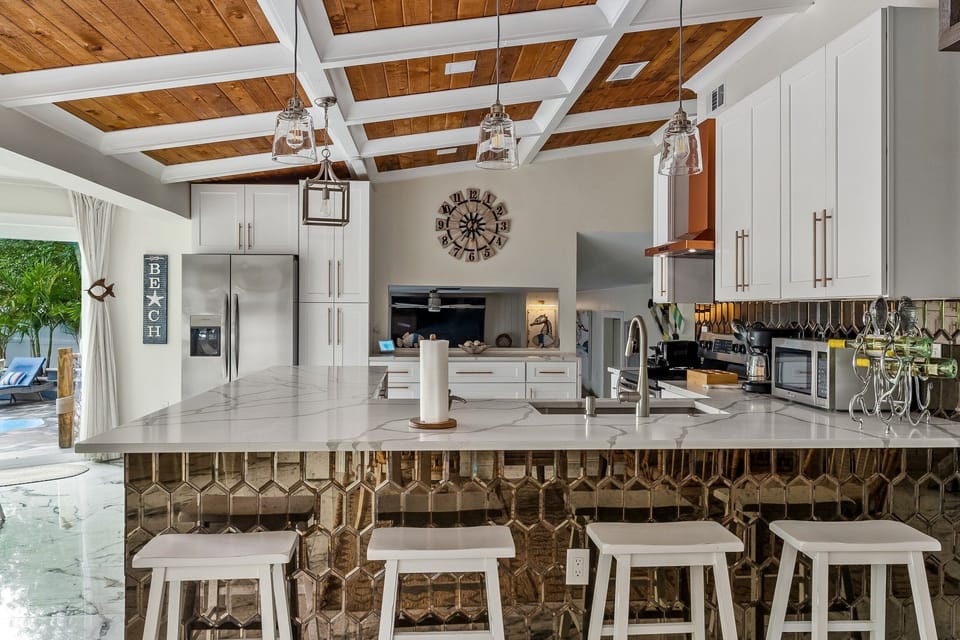 Impeccably designed Kitchen with stainless appliances, mirrored back splash, marble countertops and designer lighting