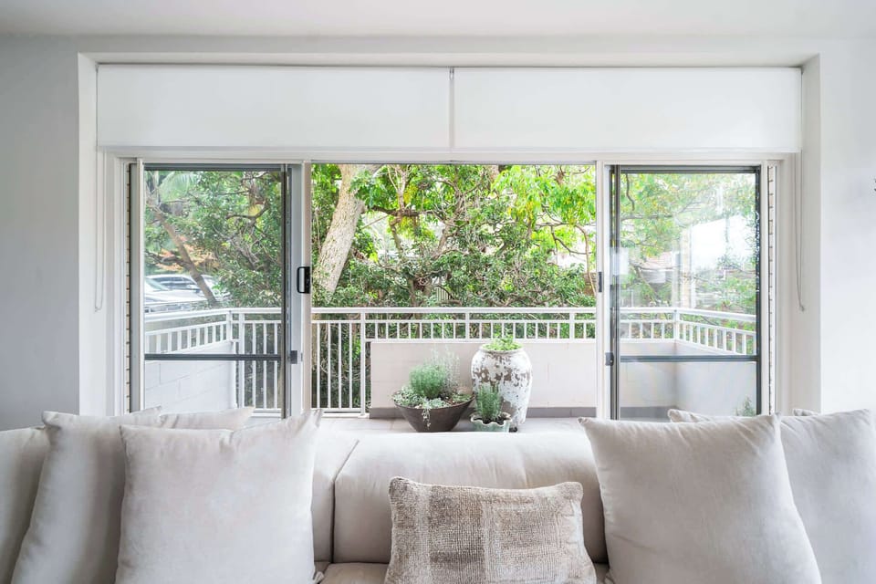 Light-filled open lounge area showcasing exquisite designer finishes and plush seating, all framed by lush greenery and balcony