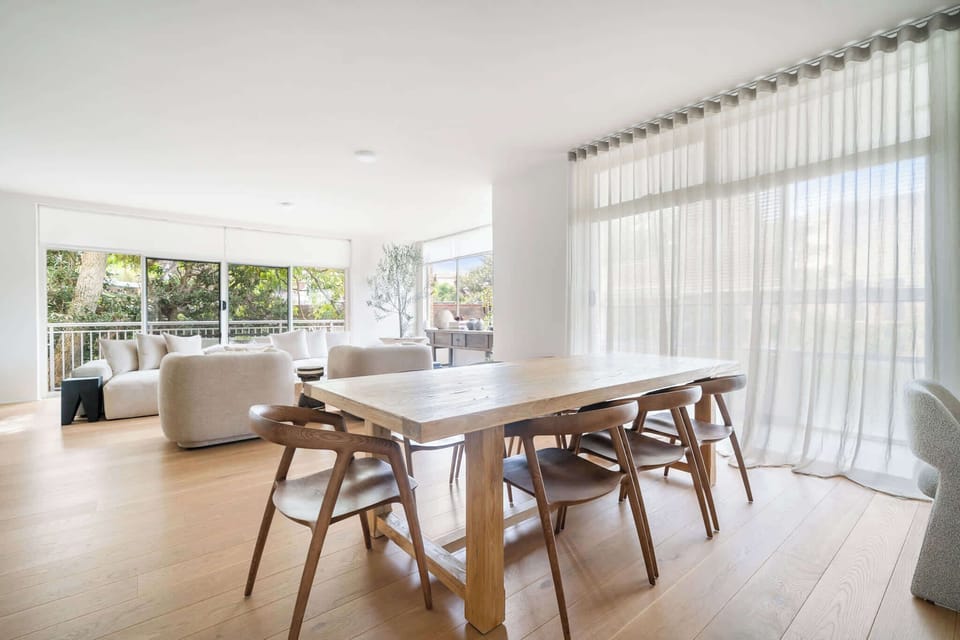 Elegant dining room with designer finishes, seating seven comfortably. Surrounded by natural light and leafy views, it offers a sophisticated setting for memorable meals and effortless entertaining.