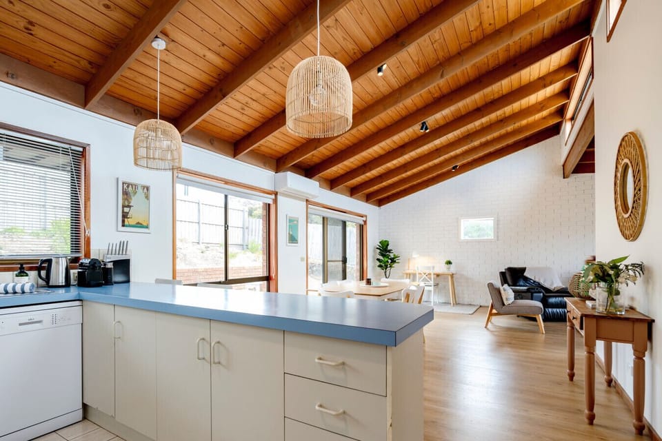 Open-plan living with high ceilings, timber beams, and abundant light