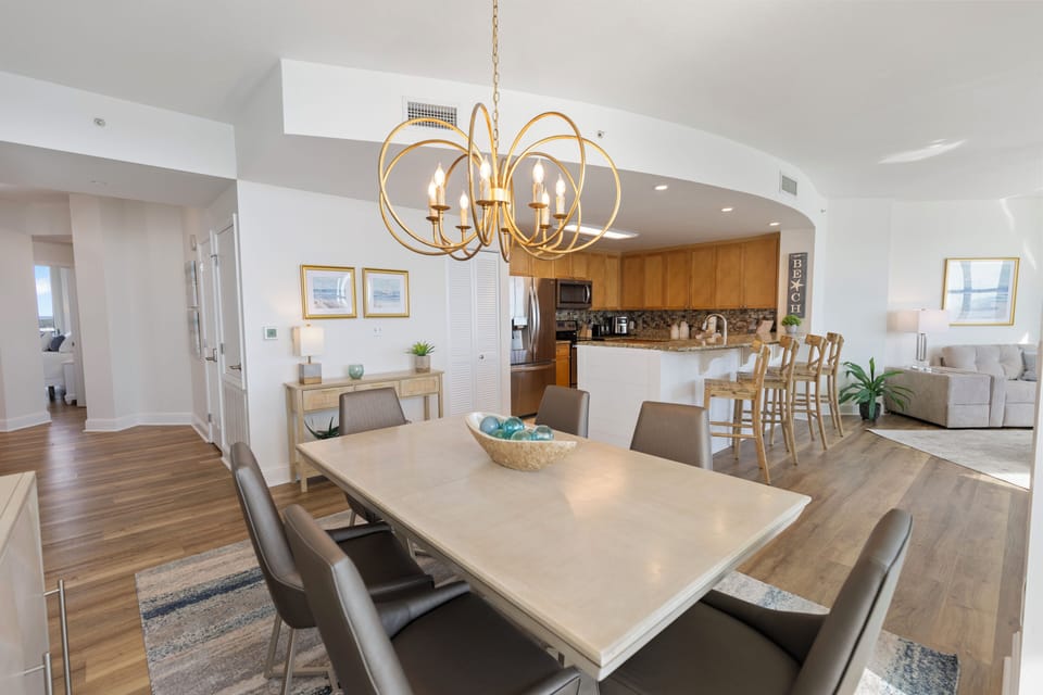 Gather around this elegant dining table where warm conversations flow beneath beautiful lighting in your open-concept space.