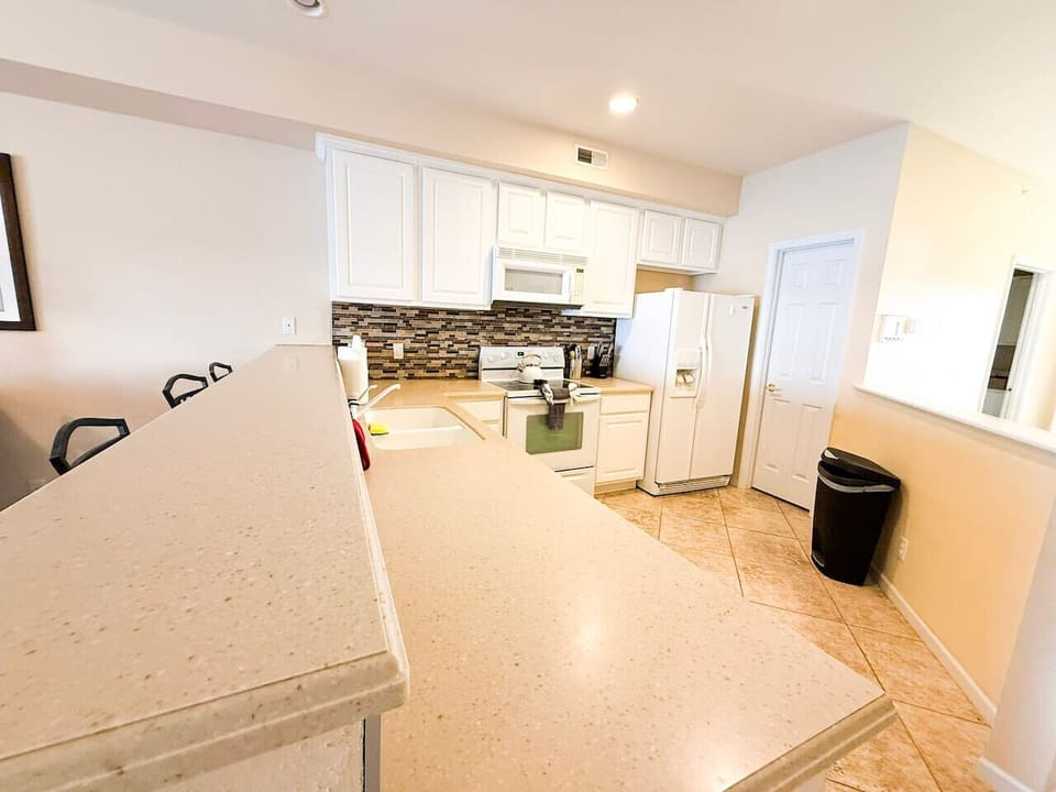 Cook and entertain with ease in this bright, fully equipped kitchen with spacious countertops, perfect for meals and gatherings.