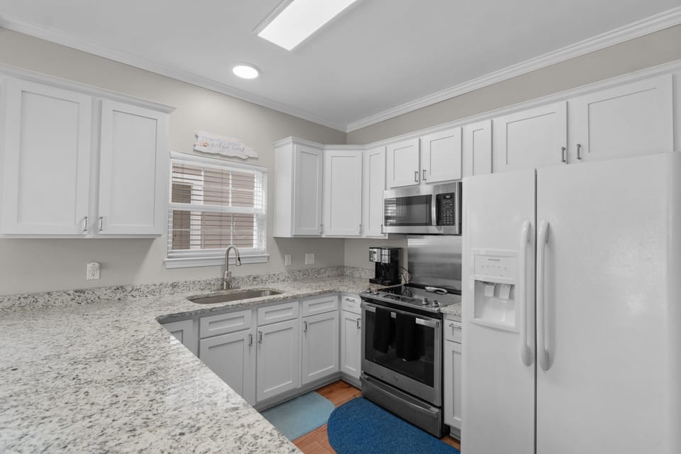 Your fully equipped kitchen features granite countertops, modern appliances, and bright white cabinetry for all your culinary needs.