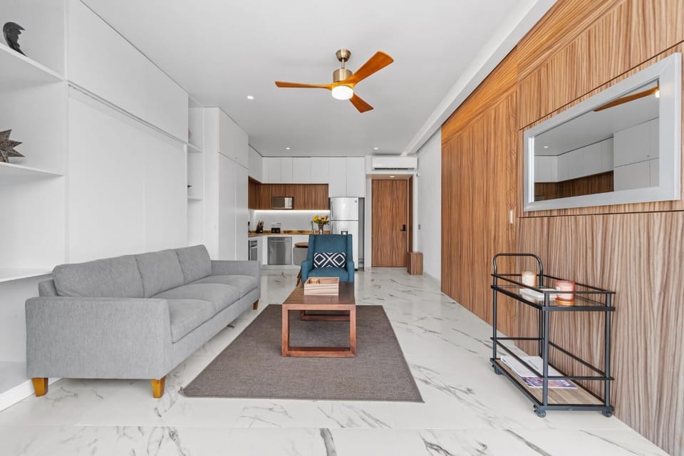 Relax in your modern open-plan living space with sleek marble floors, cozy gray sofa, and stylish wood accents throughout.