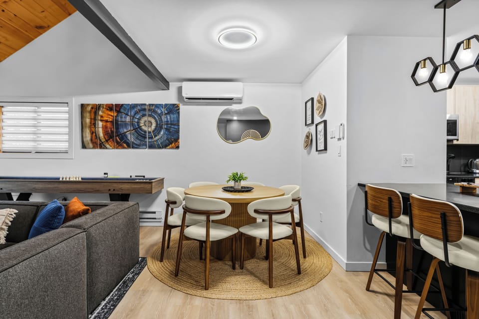 Share a meal around our stylish round wooden dining table! Features comfortable mid-century modern seating for six, plus extra kitchen island barstools nearby. Ideal open-concept layout for memorable family dinners in the Poconos.