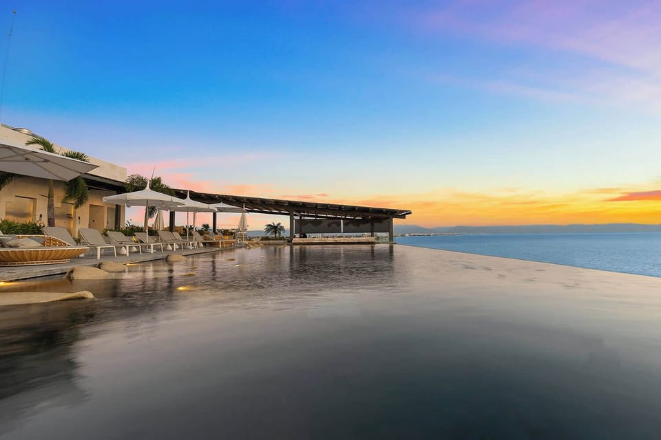 Rooftop infinity pool at sunset with endless bay views