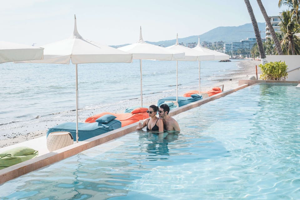 Ground floor pool with premium umbrellas and pouf loungers.