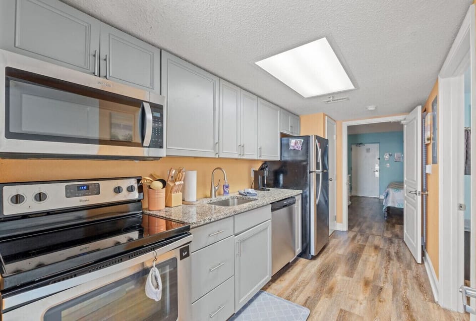 Fully equipped vacation kitchen with stove and oven, full refrigerator, dishwasher, microwave, and double sink. Includes a Keurig coffee maker, cookware, silverware, and dinnerware; perfect for easy meals during your Myrtle Beach stay.