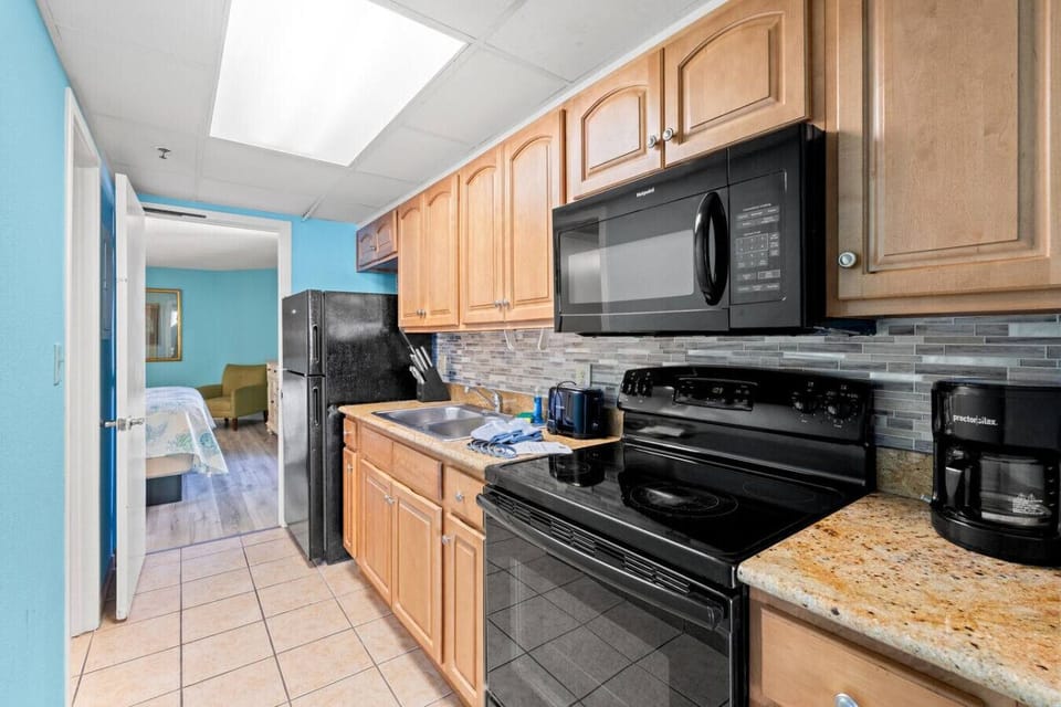 Fully stocked kitchen with full-size stove and oven, refrigerator, sink, drip coffee maker, toaster, and ample cabinet space. Includes complete dinnerware, cookware, and silverware—everything needed for simple, convenient vacation meals.