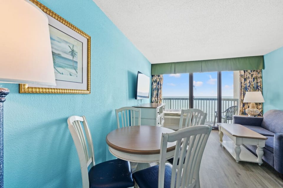 Oceanfront dining area with a table for four, filled with natural light and conveniently located beside the kitchen. Enjoy bright coastal views while sharing meals, game nights, or relaxed family gatherings by the sea.