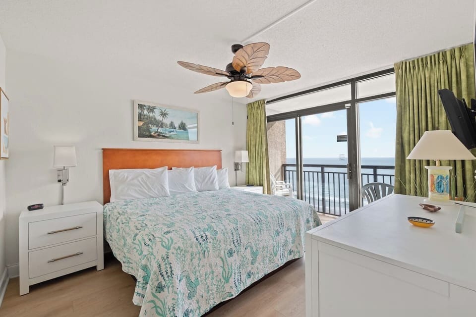 Clean, fresh master bedroom with a plush king bed, coastal décor, and stunning oceanfront views. Enjoy a private full bathroom, direct access to the oceanfront balcony, a 40` Vizio Smart TV, and ample clothing storage.
