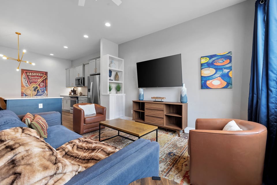 A spacious seating setup with a big TV and layered textures, styled but livable.