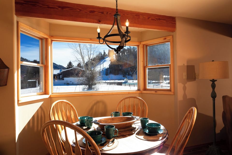 Gather around this sunlit dining table where your morning coffee tastes better with snow-covered mountains framing every meal.