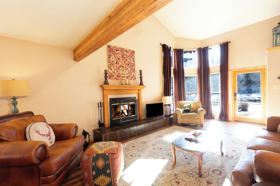 Gather around the crackling fireplace in this warm living room, where exposed beams and cozy leather seating create your perfect mountain retreat.