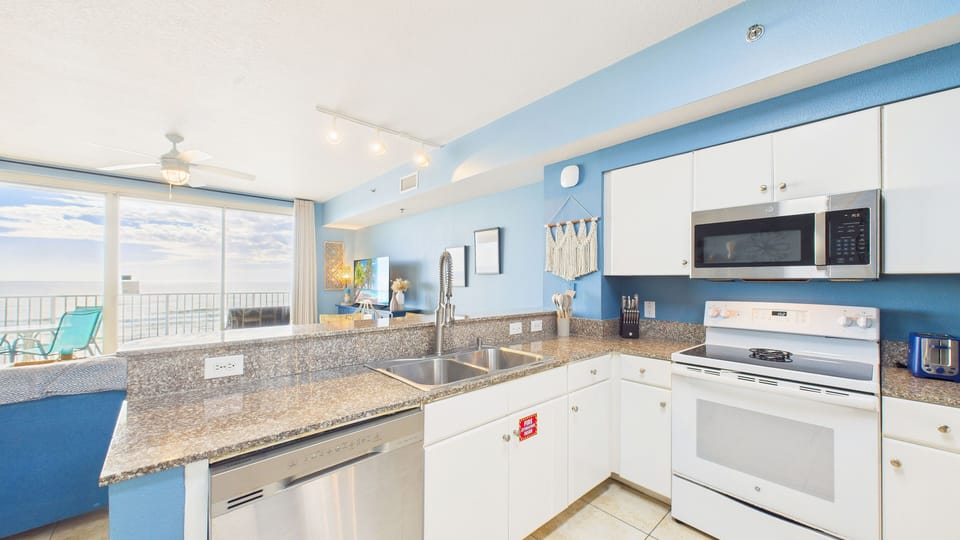 Relax in this bright coastal kitchen where ocean blues meet modern convenience, complete with granite counters and stainless appliances for your comfort.