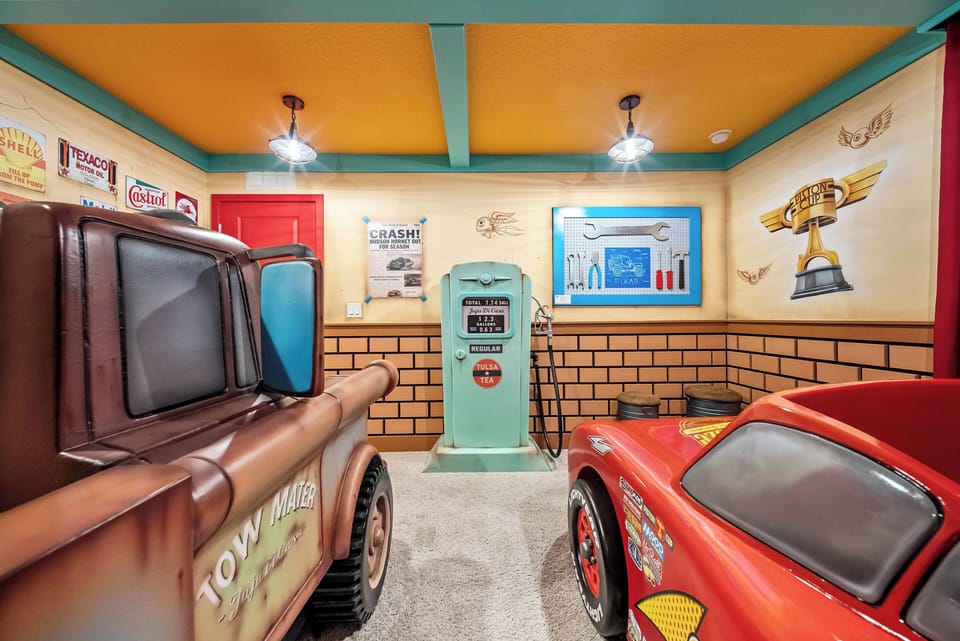 Enter a lively playroom adorned with whimsical decor and colorful walls. The vintage gas pump and charming character cars spark joy, creating a perfect space for kids and the young at heart to enjoy endless fun.