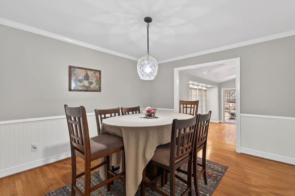 Cozy dining room accented by soft neutral tones, wood flooring, and a stylish overhead light—ideal for gatherings big or small.