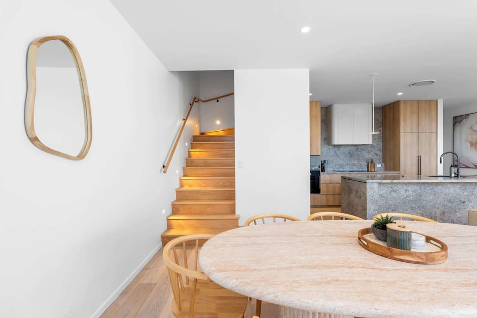 Dining space overlooking the feature timber staircase and modern kitchen, creating a cohesive and thoughtfully designed ground floor layout.