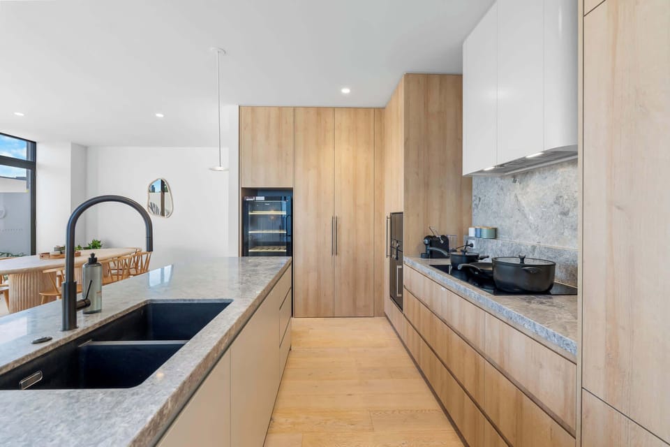 Spacious, fully equipped kitchen with stone benchtops, quality appliances, and ample workspace.