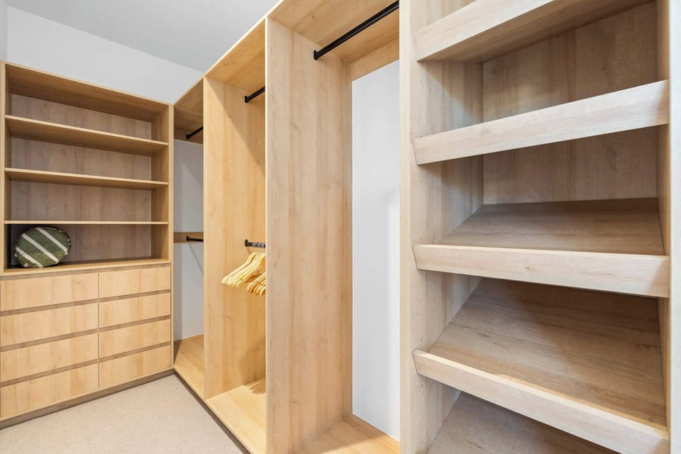 Spacious walk-in robe with custom timber shelving, drawers, and ample hanging space for extended stays.