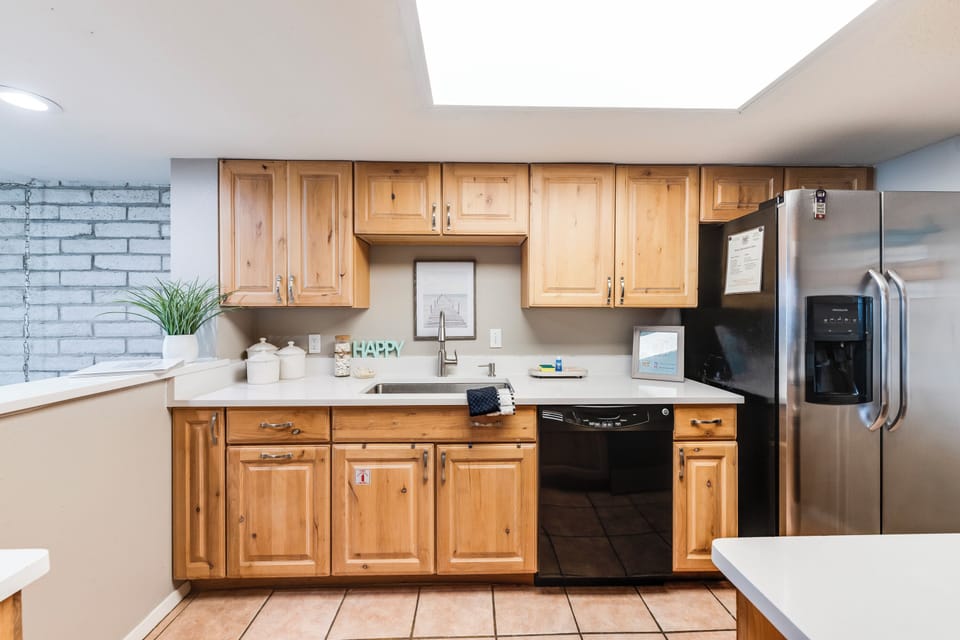 Compact, fully equipped kitchen with light wood cabinets, white counters, stainless appliances, and coastal decor touches. Gives you and your group everything you need to prepare meals during your stay.