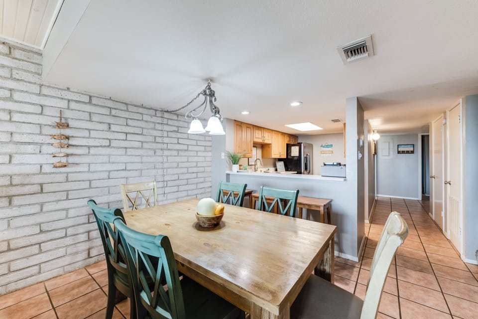 Dining area off the kitchen featuring a wooden table with mixed chairs under a chandelier, along with brick details and nearby appliances. Provides a central spot for meals and gathering.