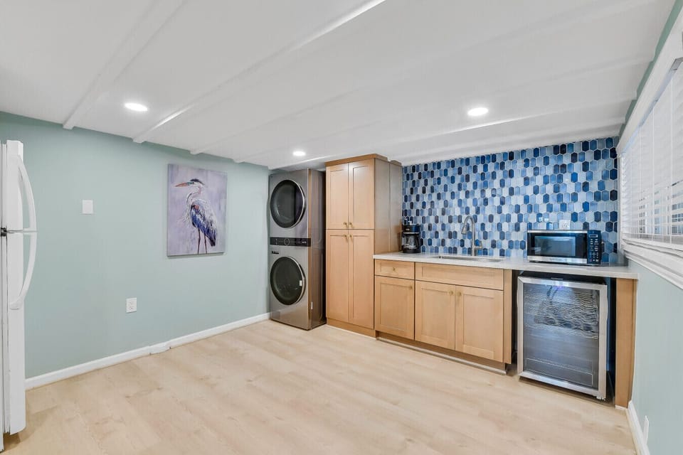 Laundry area Lower-level kitchenette with full-size refrigerator, microwave, wine chiller, and stacked washer/dryer washer and dryer.