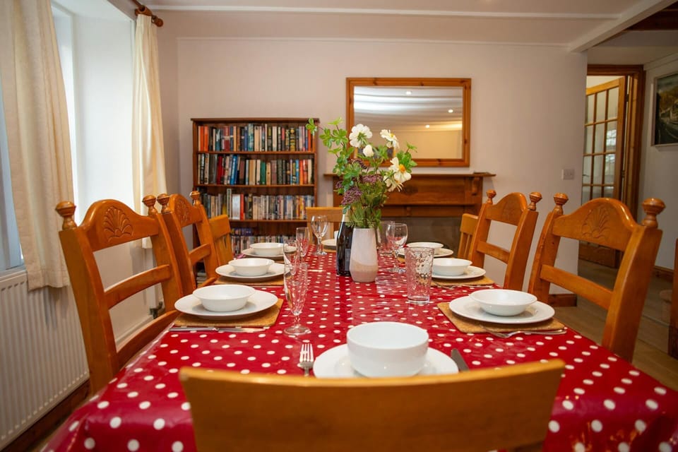 Dining room table set for a meal, with wooden chairs and a vase of flowers