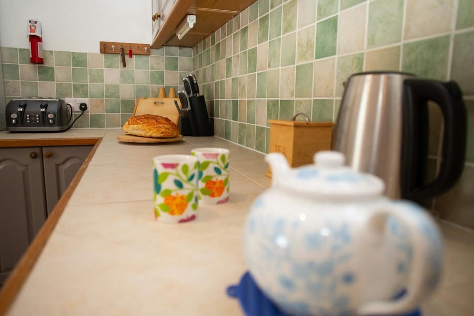 Teapot on a kitchen counter with kettle, toaster, knife block and cutting board
