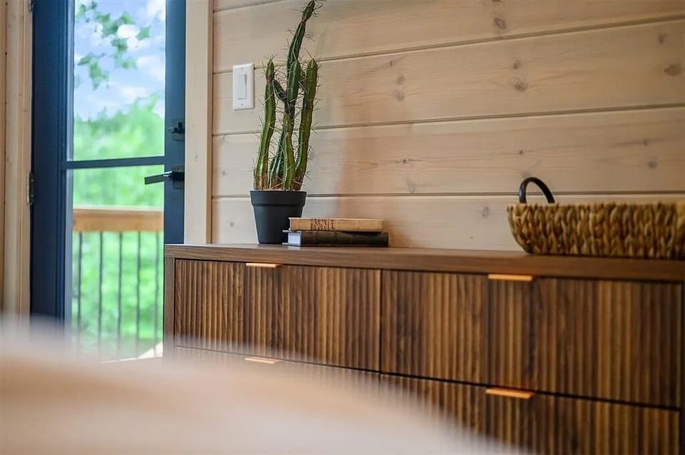 Bedroom Retreat: Stylish dresser and plants invite relaxation with tranquil views of nature!
