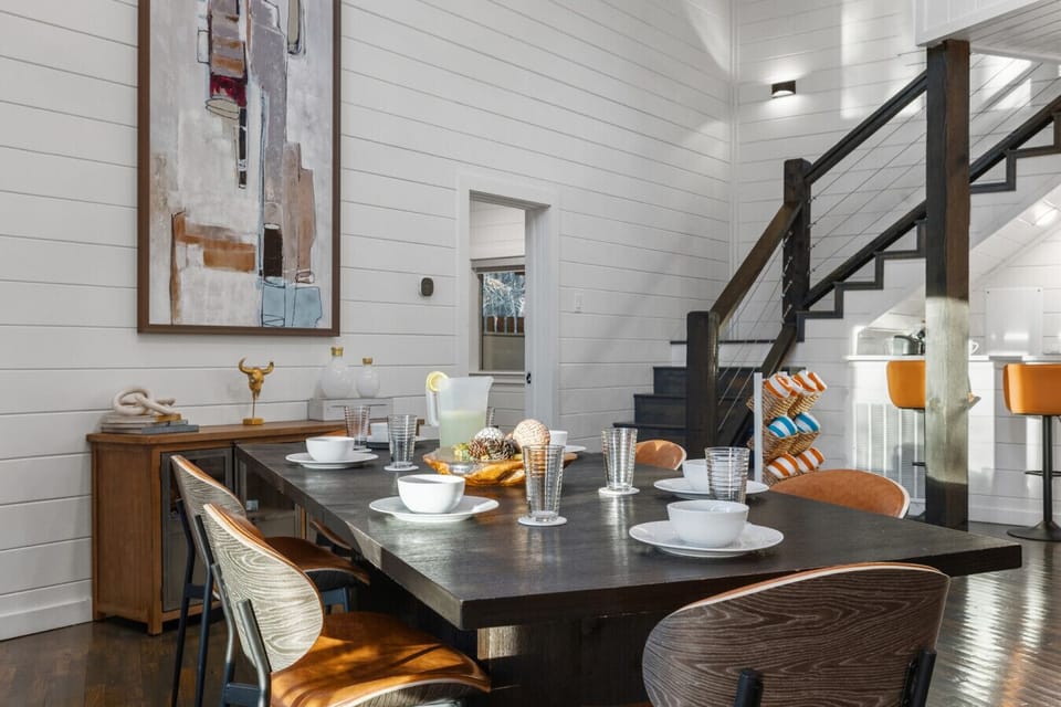 Dining table styled with full place settings — white shiplap wall, modern art, and staircase backdrop create an upscale, magazine-worthy dining atmosphere.