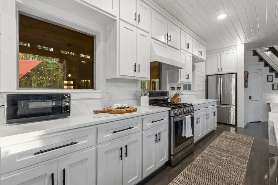 Open-concept gourmet kitchen with full white cabinetry, stainless appliances, gas range, double oven & oversized island — designed to host 14 guests effortlessly.
