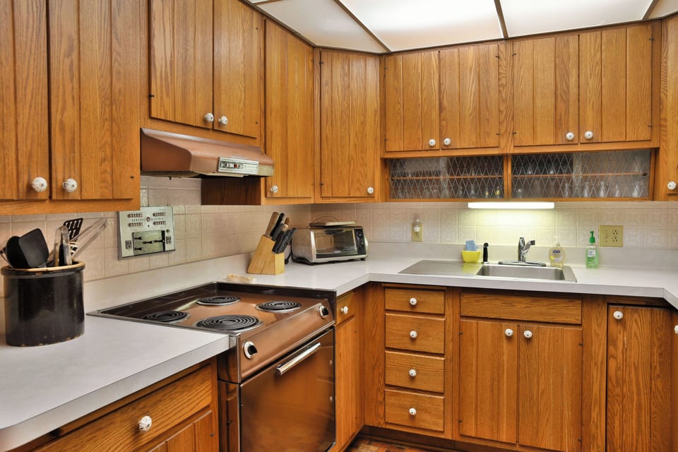 Compact kitchen at Elk Crossing Lakehouse featuring wood cabinets, white countertops, a tiled floor, and a white refrigerator.