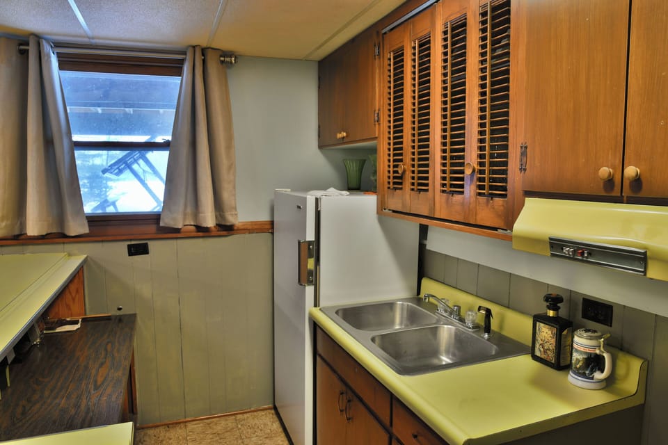 Compact kitchen area at Elk Crossing Lakehouse featuring a double stainless steel sink, and a  refrigerator.