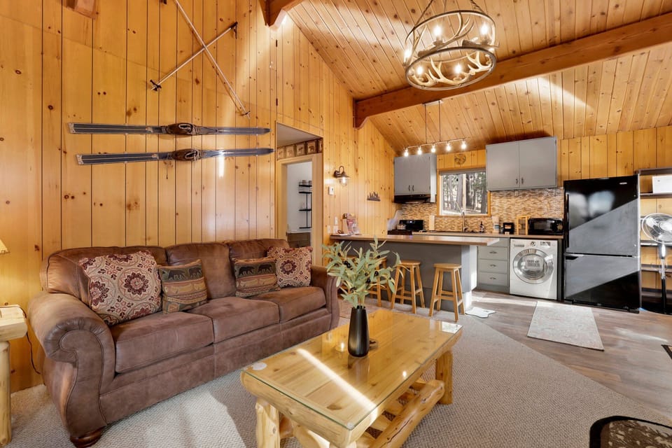 Cozy mountain living room with a stone fireplace, comfy seating, and smart TV—perfect for relaxing evenings, movie nights, and warm cabin vibes after outdoor adventures.