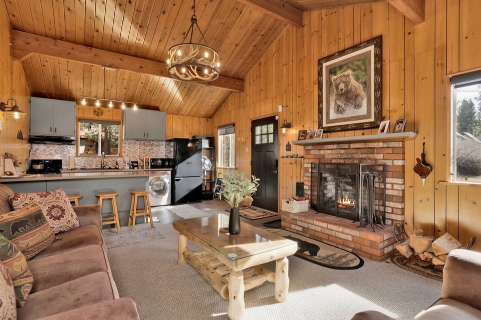 Cozy mountain living room with a stone fireplace, comfy seating, and smart TV—perfect for relaxing evenings, movie nights, and warm cabin vibes after outdoor adventures.