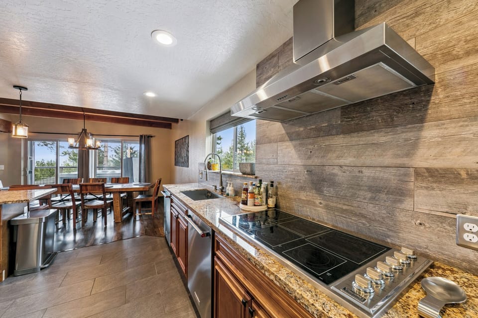 Cook memorable meals in your stunning kitchen featuring granite counters, premium appliances, and rustic wood backsplash opening to dining space.