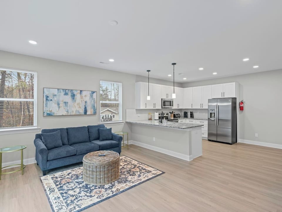 Spacious living room featuring comfortable seating and a 65” wall-mounted TV with streaming services. Ideal for movie nights or unwinding together.