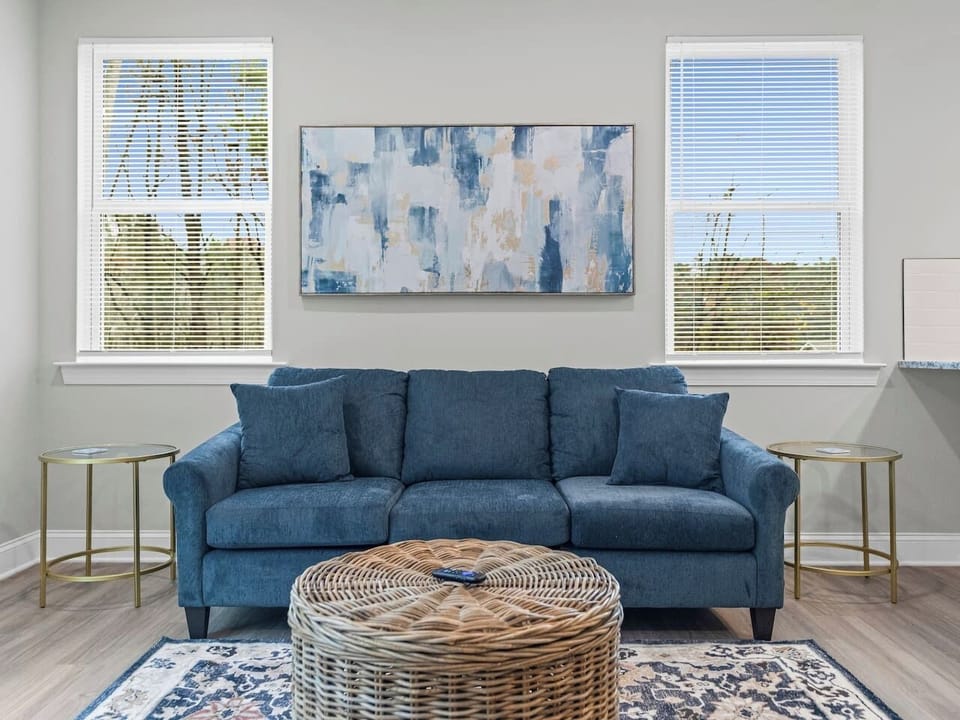Inviting living room featuring ample seating, a 65` wall-mounted TV with streaming services, and a bright, open layout.