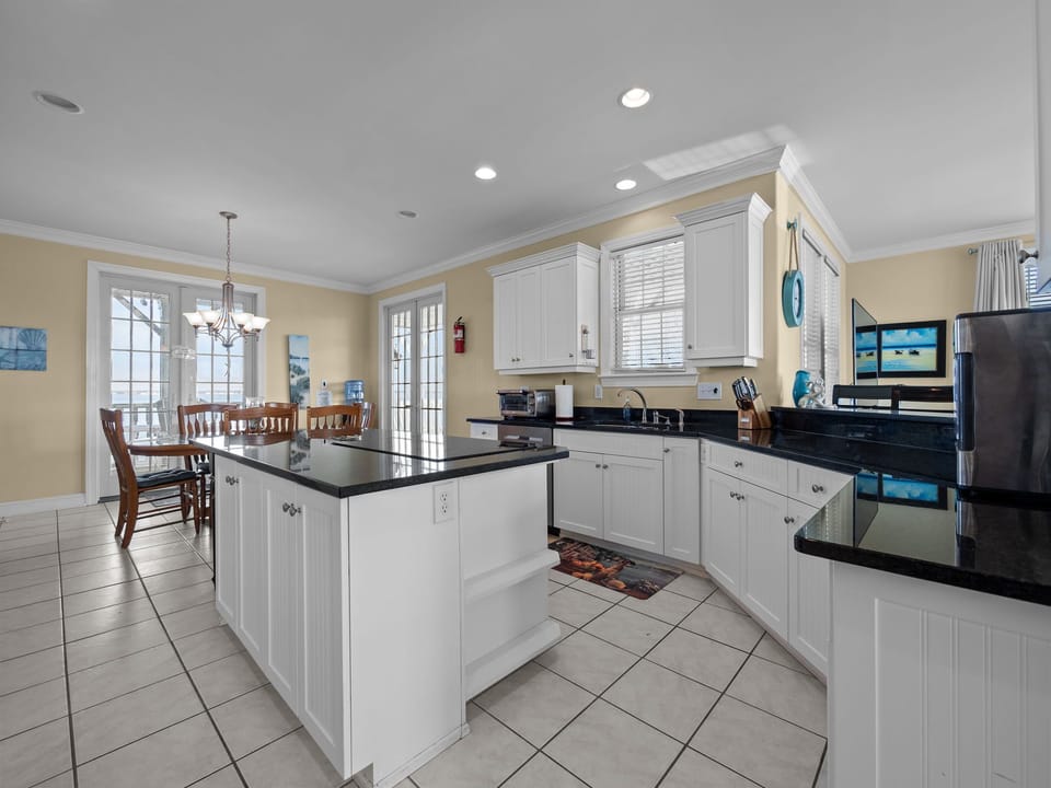 Your spacious kitchen invites culinary adventures with its gleaming granite countertops, bright white cabinets, and modern black appliances.