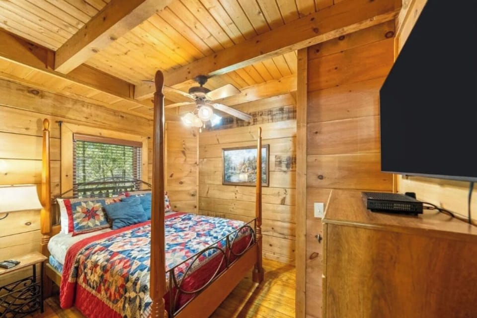 Cozy up in your rustic four-poster bed beneath soaring wood beams, where quilted comfort meets mountain charm in this beautiful log cabin bedroom.