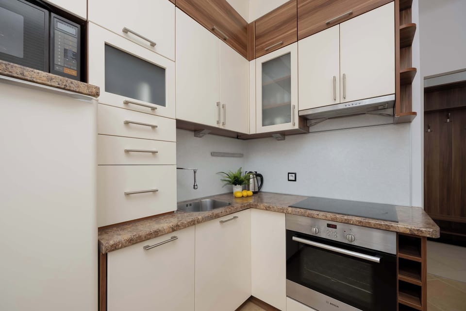 A corner kitchen view highlighting upper cabinets and cooking space. Wood and white tones create a warm contrast. The layout looks efficient and tidy.