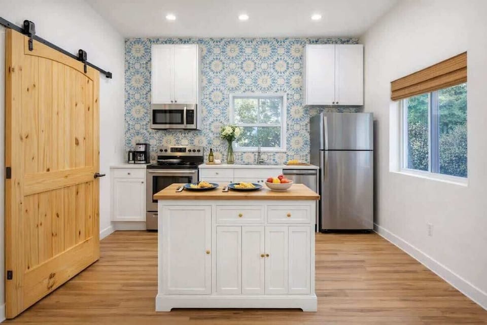 Bright, fully equipped kitchen with modern appliances, a spacious island, and beautiful Mediterranean-inspired tile. Cook, dine, and gather in a warm, inviting space designed for easy meals and memorable moments at Teeni Santorini.
