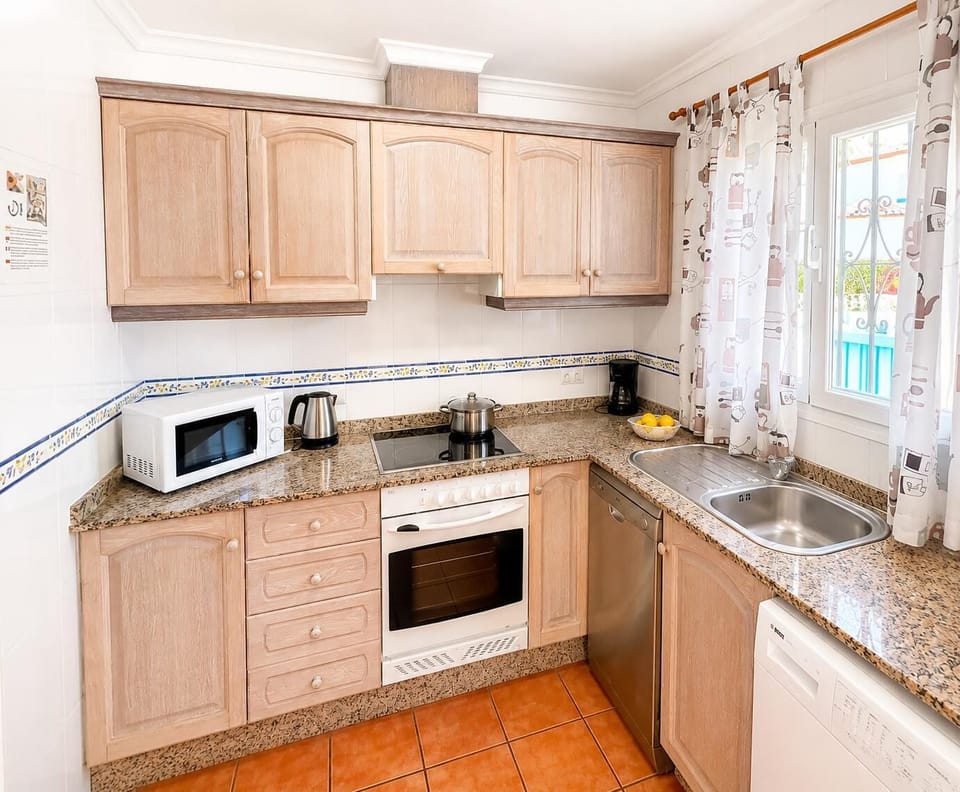 This fully equipped self-catering kitchen features spacious wooden cabinetry, modern appliances, and granite countertops, providing everything you need for an effortless Mediterranean villa holiday.