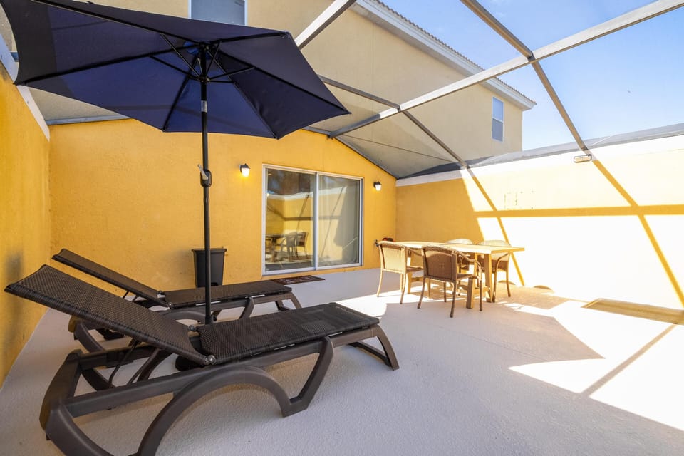 Sunlit screened patio with loungers and dining area