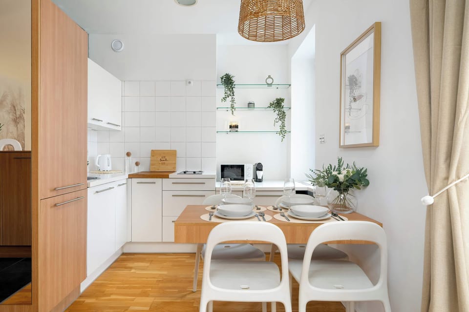 Modern kitchenette with white cabinetry, wooden countertop, and compact dining table.
