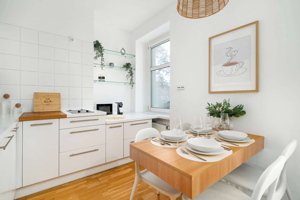 Modern kitchenette with white cabinetry, wooden countertop, and compact dining table.