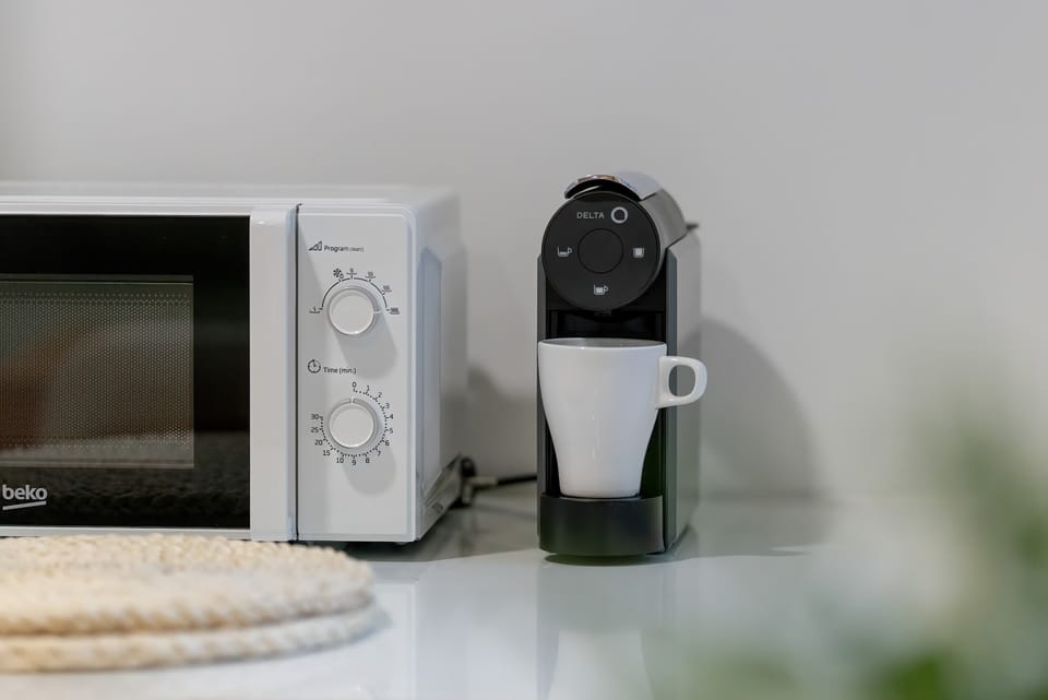 Compact kitchen detail with microwave, coffee machine, and neatly arranged accessories.