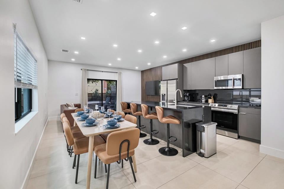 Modern kitchen and dining area with seating for ten and a sleek black island.